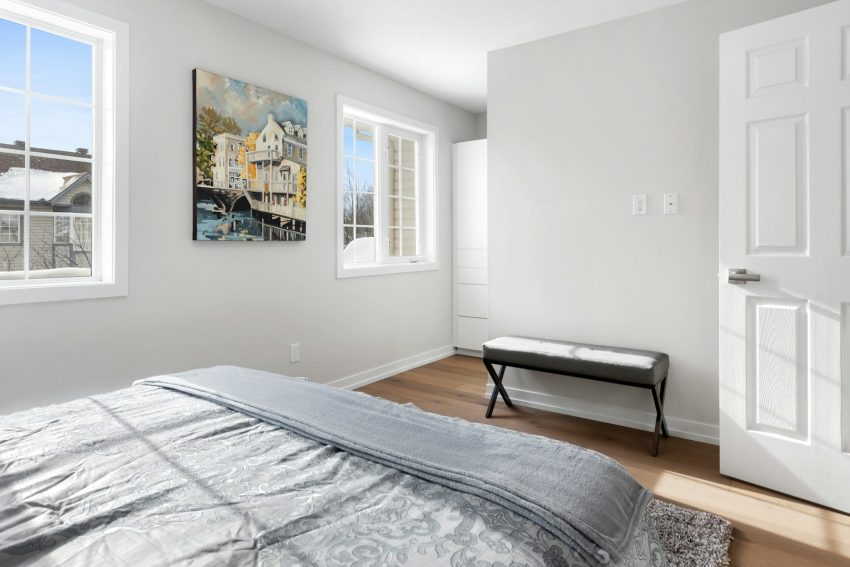 a bedroom with a large bed and two windows