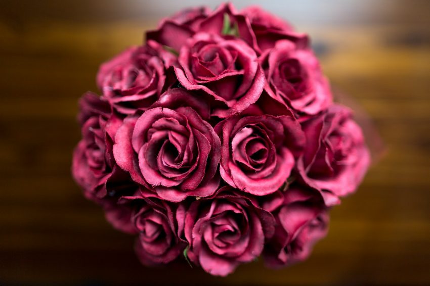 a bouquet of pink roses sitting on top of a wooden table